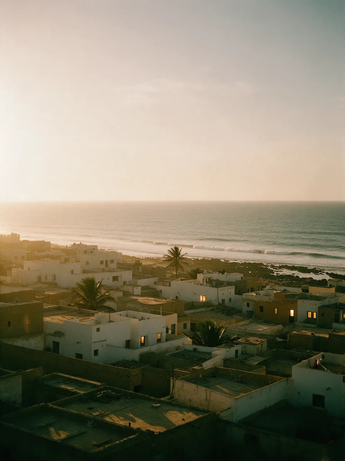 Low rooftops of a coastal city facing the Atlantic at dusk.